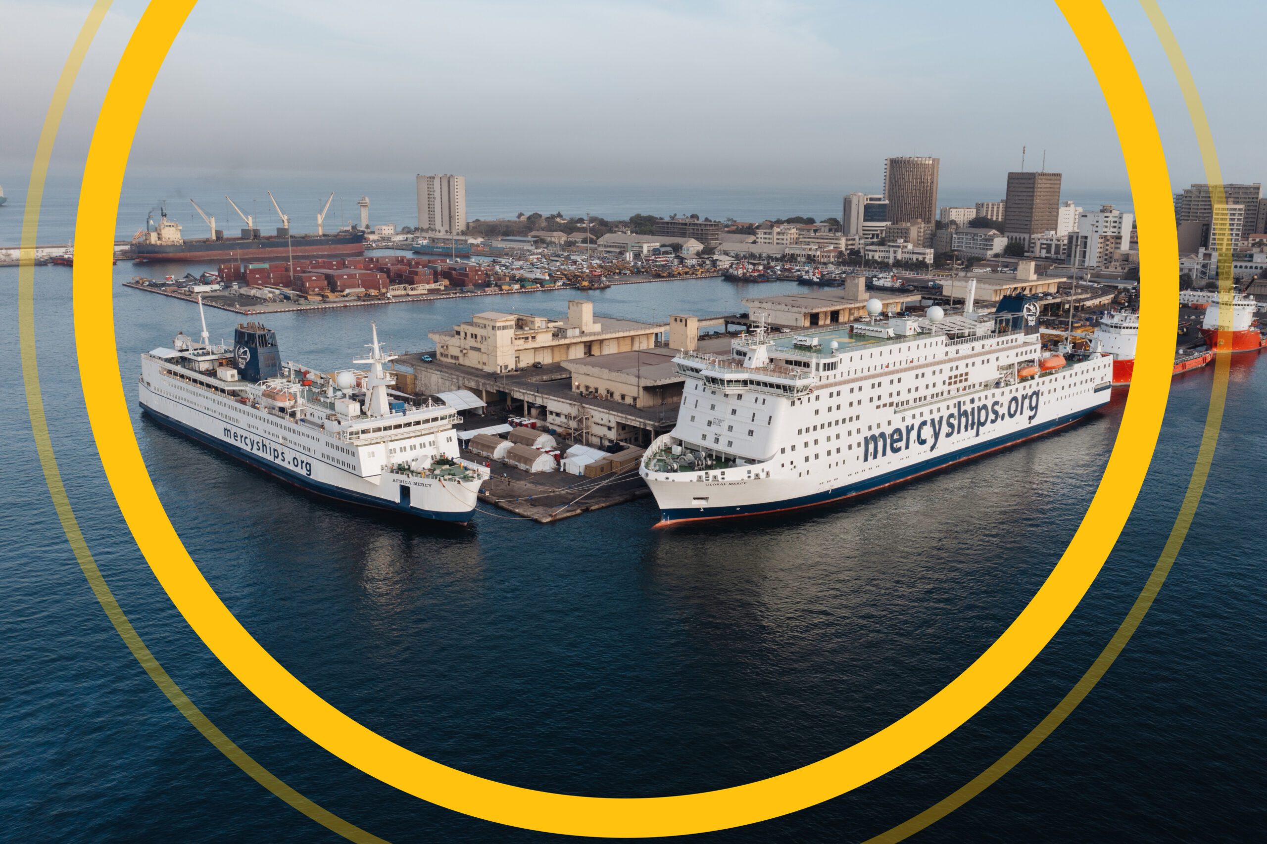 Two Mercy Ships' vessels docked at a port.